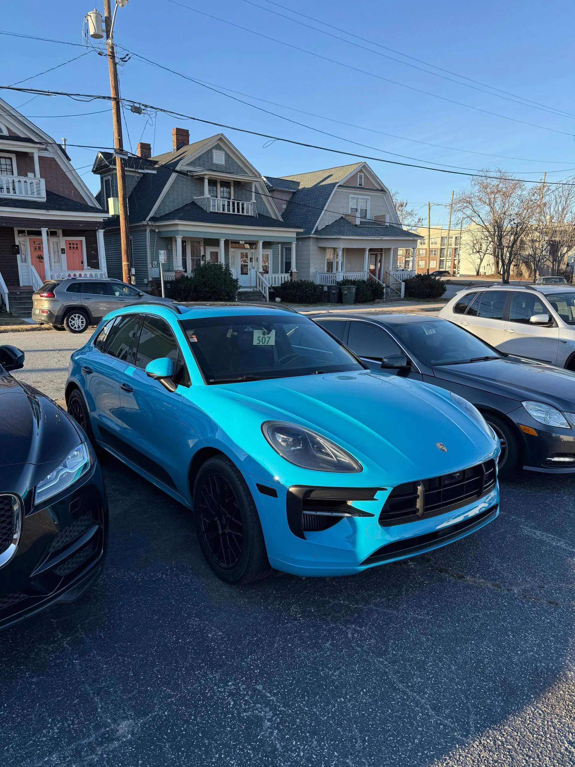 Bright blue Porsche sports car parked among other cars on a sunny street