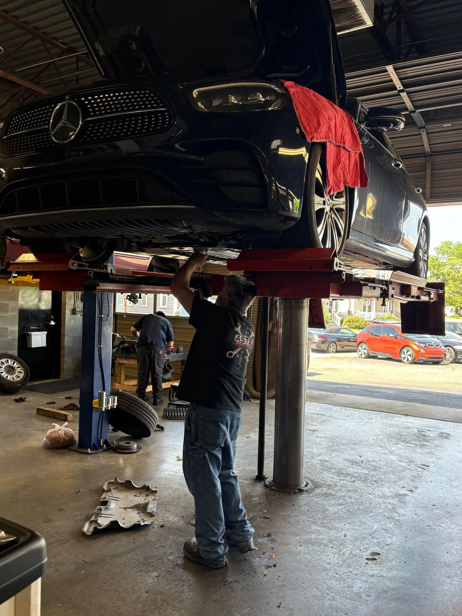 Mechanic working under a raised black vehicle