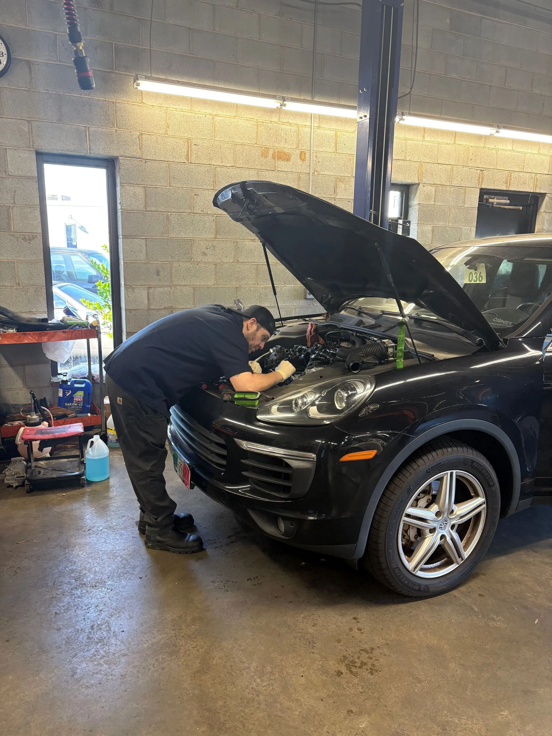 Mechanic working under the hood of a black SUV
