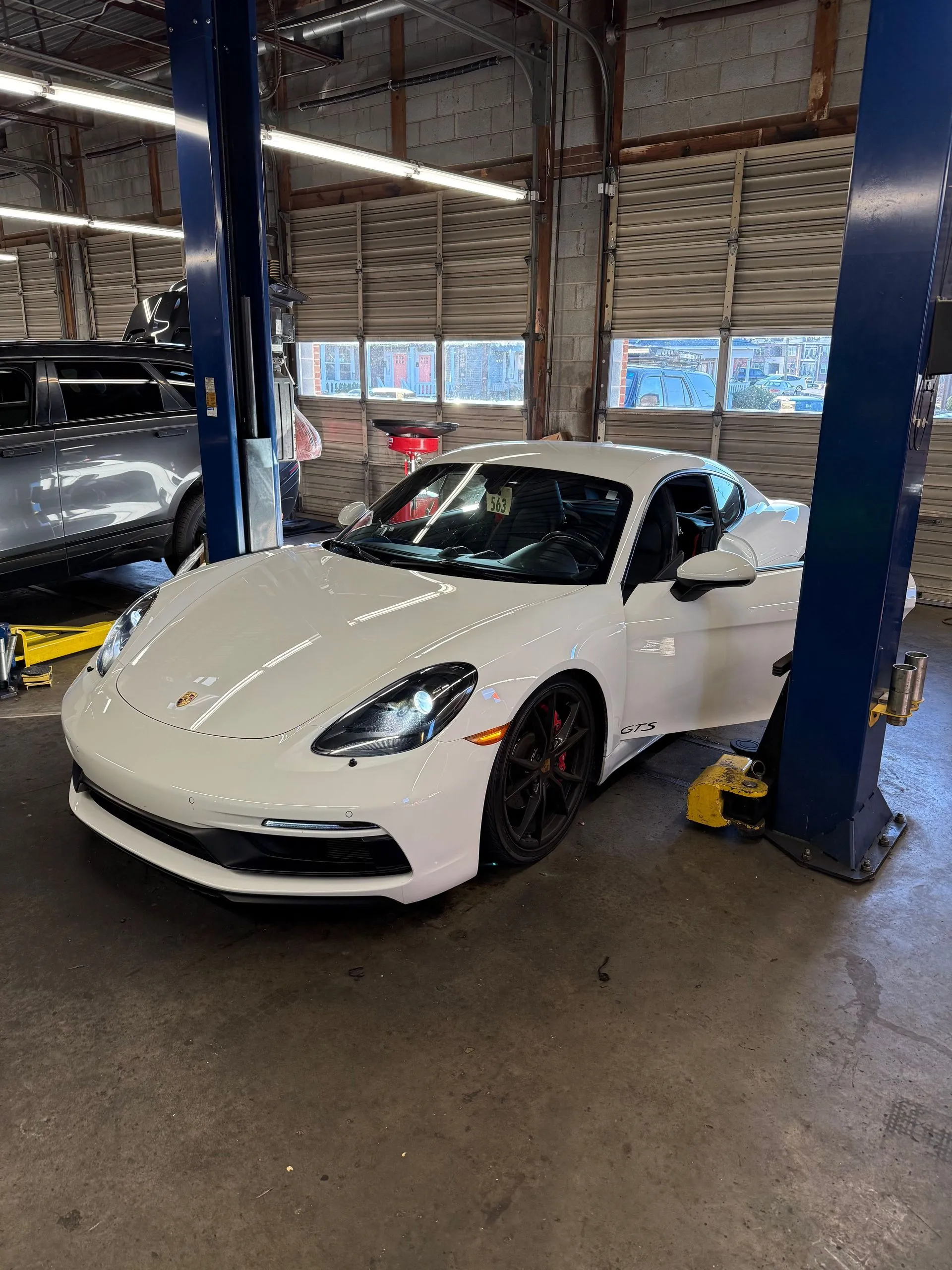 White sports car in a garage bay between lifts